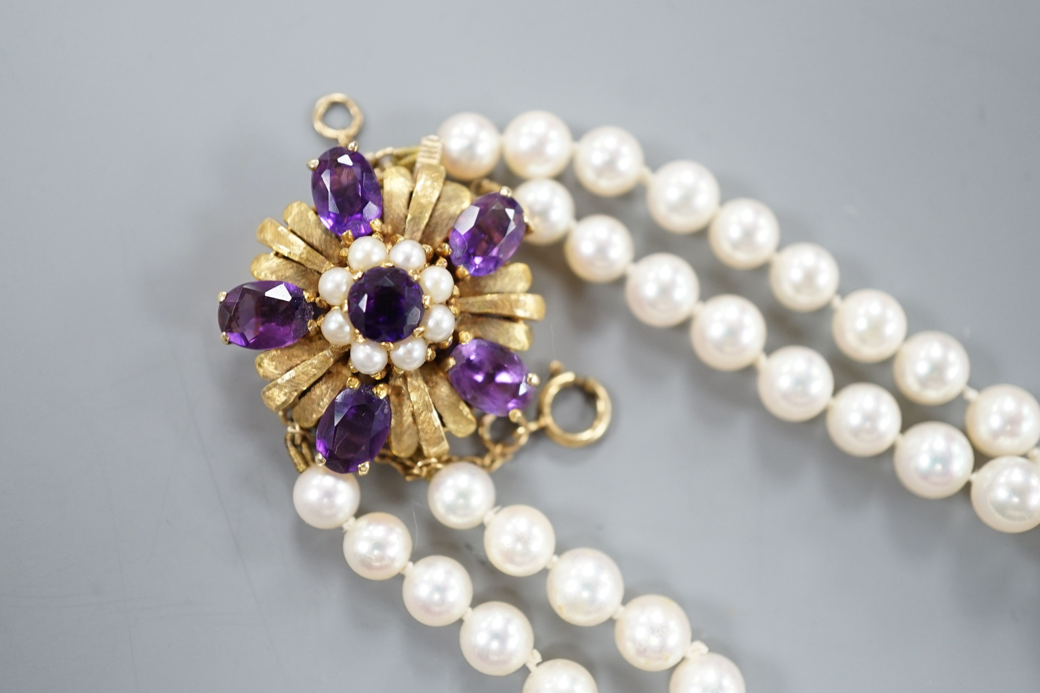 A modern double strand graduated cultured pearl necklace, with amethyst and cultured pearl cluster set 9ct clasp, 42cm.